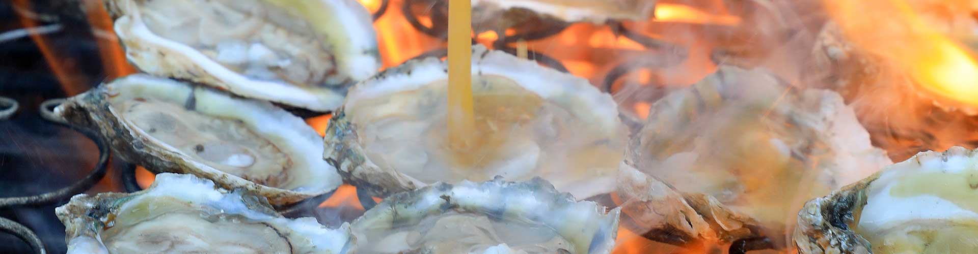 Oysters placed on a grill, with a spoon nearby, illustrating a culinary experience of grilling seafood.